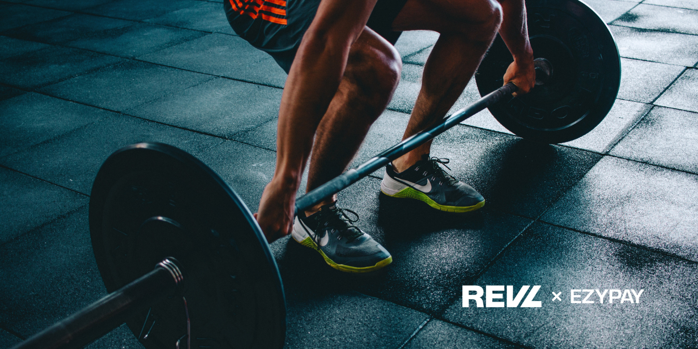 A person is engaged in a squat exercise with a barbell, showcasing their workout routine in a gym.