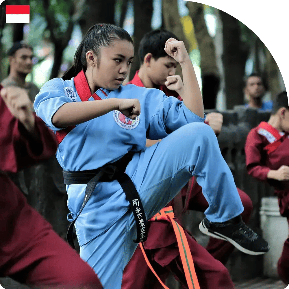 Martial arts class practicing outdoors; young students in colorful uniforms perform synchronized kicks and punches, conveying focus and energy.