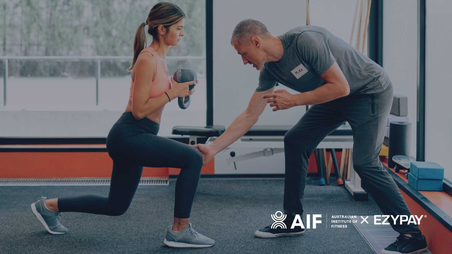 A man and woman exercising in a gym, doing squats to improve their physical fitness and endurance. The logos for the Australian Institute of Fitness and Ezypay appear in the lower right hand corner of the image. 