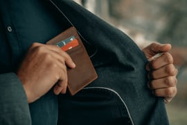 A man removing his wallet from the inside pocket of his jacket.