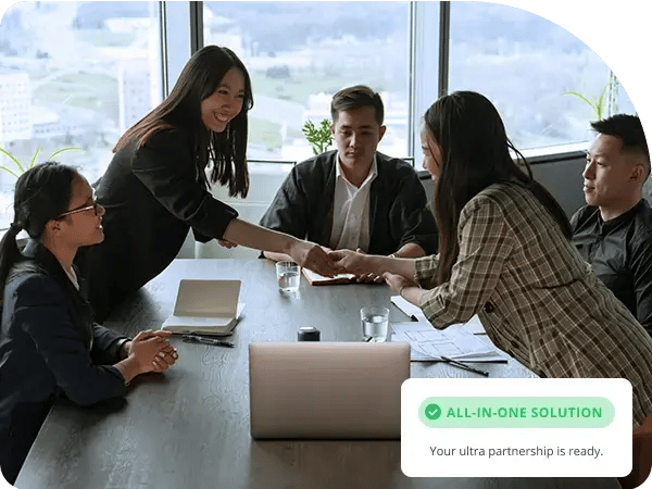 colleagues shaking hands over a desk 