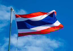 The Thai flag flying against a blue sky.