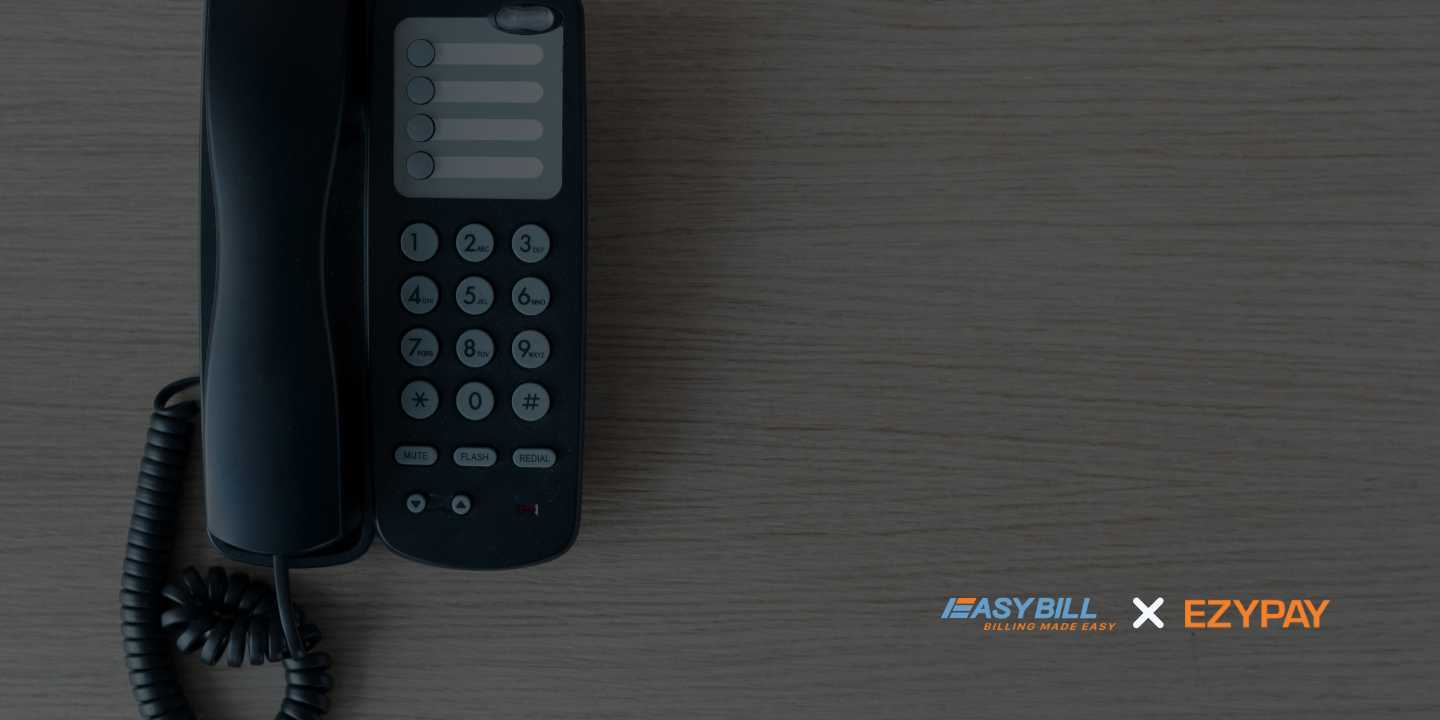 A black landline phone on a wooden surface, with EasyBill and Ezypay logos visible in the lower right corner.