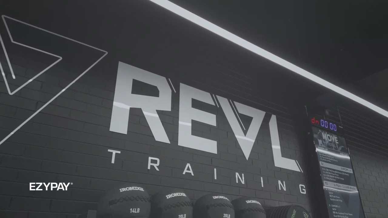 A wall displays the Revl Training logo, highlighting the brand's commitment to athletic training and development. Below it sits the Ezypay logo in white.